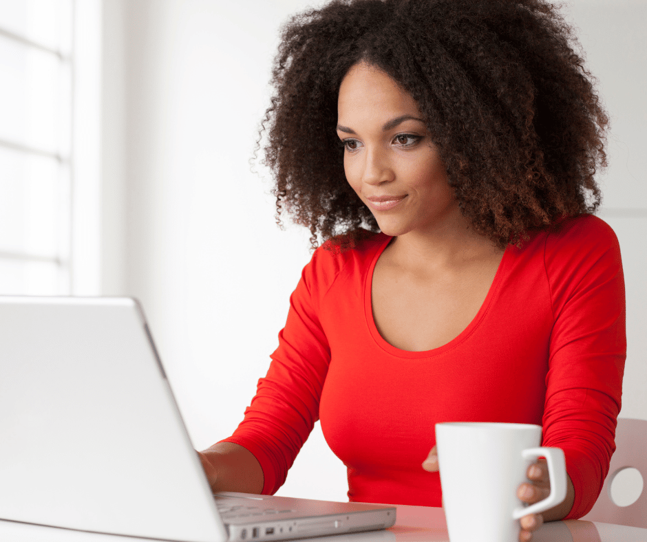 woman looking at laptop computer coffer mug in hand